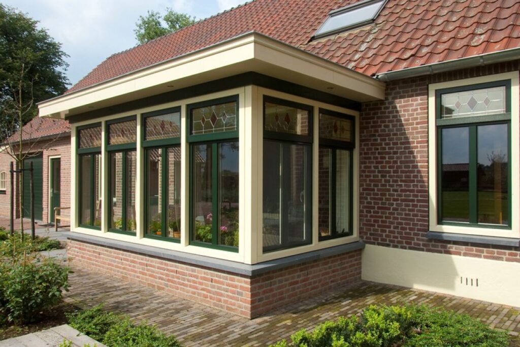 Klassieke serre/uitbouw met groen-crème kozijnen en grote ramen