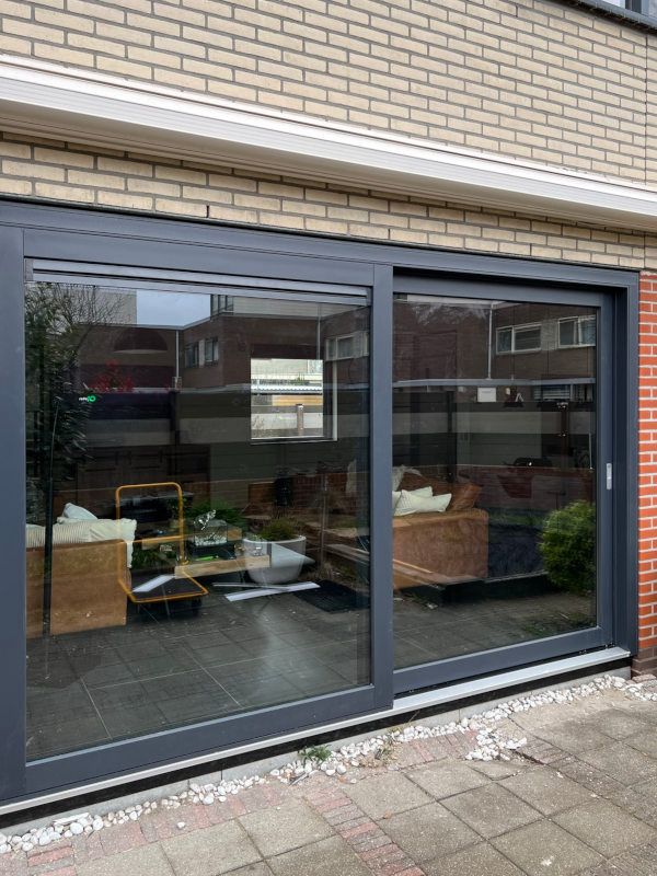 Donkergrijze aluminium schuifpui aan voorgevel met groot glas