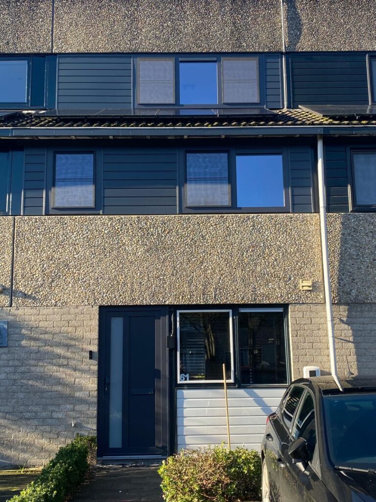 Donkerblauwe voordeur en kozijnen met vernieuwde gevelpanelen aan voorgevel